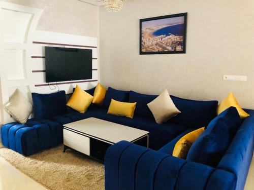 een woonkamer met een blauwe bank en een tv bij L impérial appart haut founty in Agadir