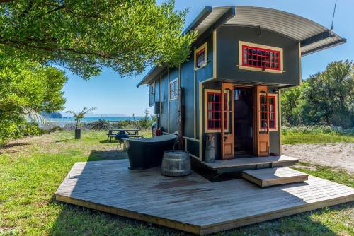 a tiny house sitting on a wooden deck at Golden Bay Hideaway in Takaka