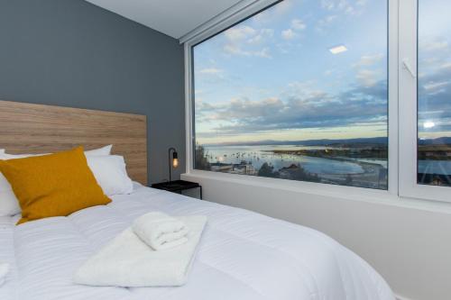 a white bed with a large window in a bedroom at Pacifico Departamentos in Ushuaia