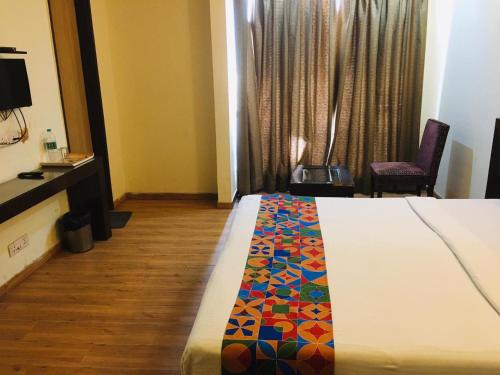 a bedroom with a bed with a colorful blanket on it at Hotel Merriment Alpha in Noida