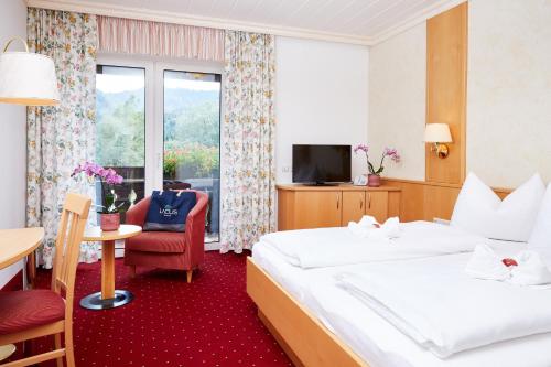 a hotel room with two beds and a television at LACUS Hotel am See in Weissensee