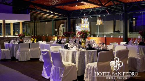 a row of tables with white table linens and chairs at Hotel San Pedro Puebla in Puebla