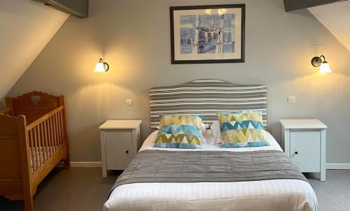 a bedroom with a bed with two tables and a crib at Les Mouettes in Escalles