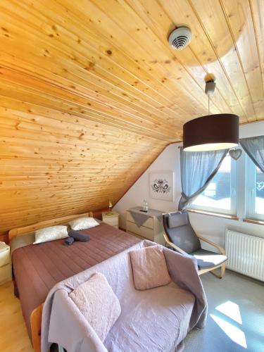a bedroom with a wooden ceiling with a bed and a chair at Karczma Kubalonka in Istebna