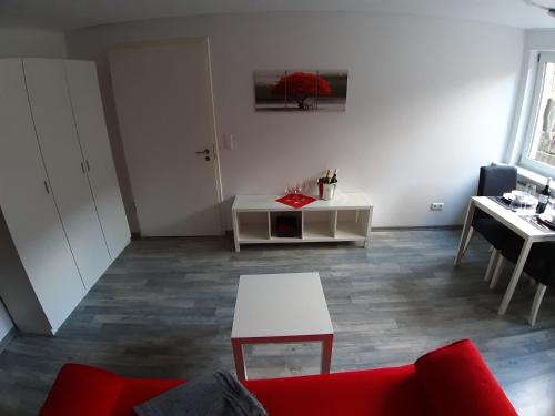 een woonkamer met een rode bank en een witte tafel bij Ferienwohnung im schönen Zellertal in Wachenheim