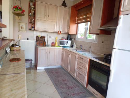 a kitchen with white cabinets and a sink and a microwave at The nearest apt to the airport in Artemida