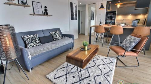 un salon avec un canapé bleu et une cuisine dans l'établissement Le Jet 7 - Appartement de standing avec belle vue mer, à Pléneuf-Val-André