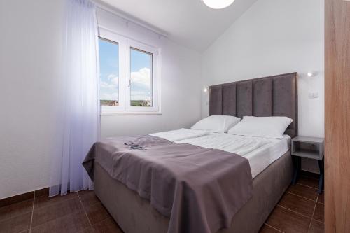 a white bedroom with a large bed and a window at Villa Mona Apartments in Ražanj