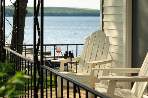 two white chairs sitting on a porch overlooking the water at Silver Birches Resort in Hawley
