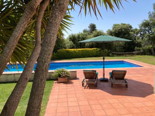 un patio con sillas y una sombrilla junto a la piscina en Mar y Emma, en Vall-Llobrega