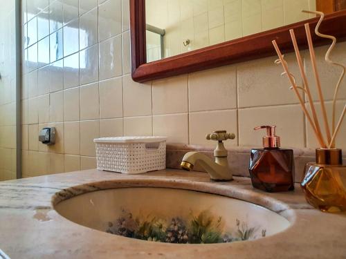 eine Badezimmertheke mit einem Waschbecken und einem Spiegel in der Unterkunft Casa 4 dorms 2 suites - localização perfeita no centrinho e rodeada de natureza in Alto Paraíso de Goiás