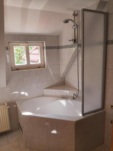 baño con bañera blanca y ventana en Garni-Pension Andrä, en Schierke