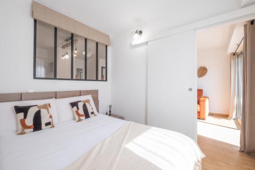 une chambre avec un lit blanc et un miroir dans l'établissement  Idéal famille  Appartement tout confort dans résidence avec piscine !, à Cannes