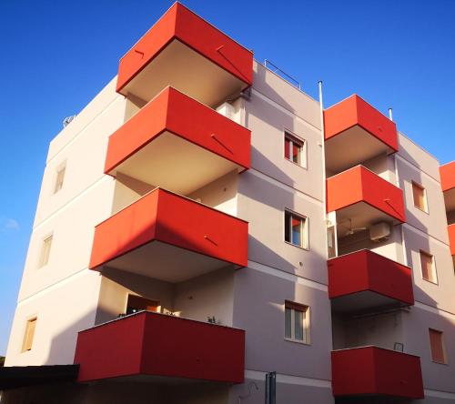 un edificio con balcones rojos. en House Lido en Gallipoli