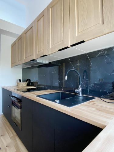 a kitchen with wooden cabinets and a sink at Apartamenty Osmolice w Stawach in Dęblin