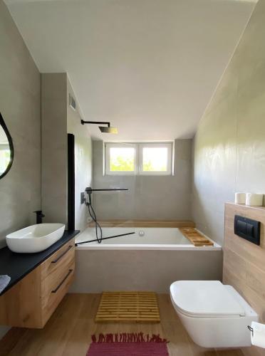 a bathroom with a tub and a toilet and a sink at Apartamenty Osmolice w Stawach in Dęblin
