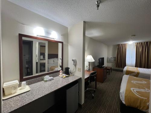 a hotel room with a bed and a desk with a mirror at Quality Inn Mitchell I-90 in Mitchell