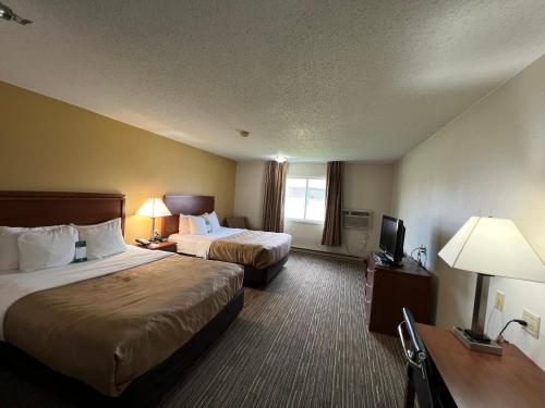 a hotel room with two beds and a television at Quality Inn Mitchell I-90 in Mitchell