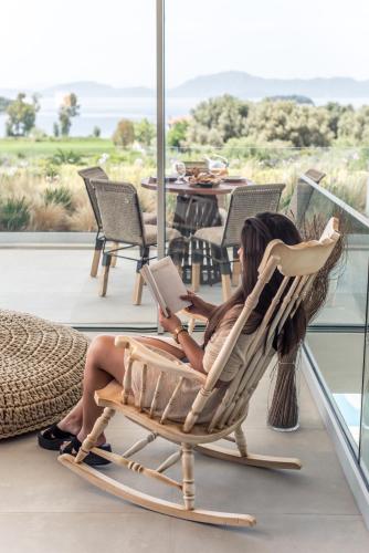 a woman sitting in a rocking chair with a laptop at VARKO LUXURY SUITES in Paleros
