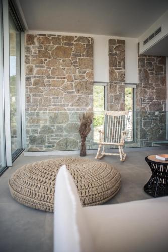 a living room with a chair and a stone wall at VARKO LUXURY SUITES in Paleros