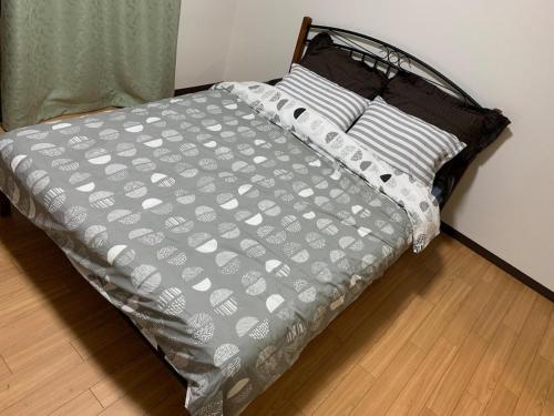 a bed with a gray comforter and two pillows at Jinpachi Building - Vacation STAY 64315v in Gifu