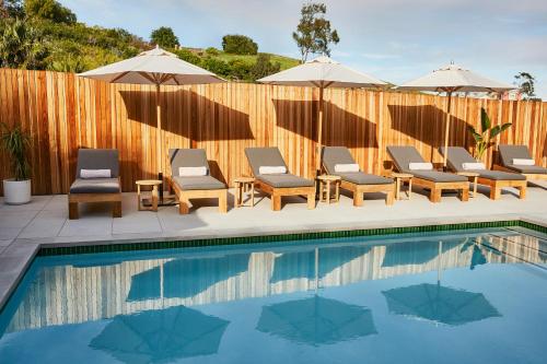 a pool with chairs and umbrellas next to a fence at Hotel June Malibu in Malibu