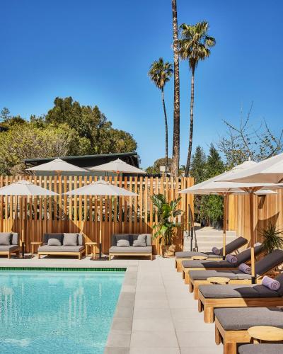 a pool with chaise lounge chairs and umbrellas at Hotel June Malibu in Malibu