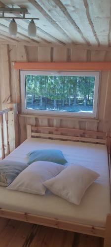 a bed in a small room with a window at ŠMITI in (( Čūskumuiža ))