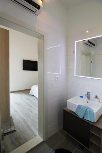 a bathroom with a sink and a mirror at Apartman Cicibella in Kaštela