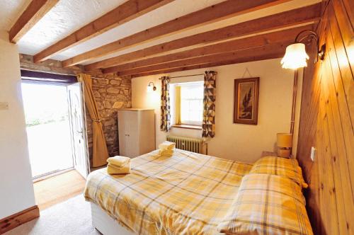a bedroom with a large bed with a yellow plaid blanket at Cosy cottage for 2, sea views, large grounds. WiFi in Newport