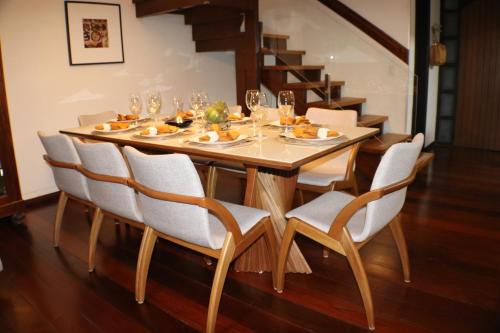 einem Esstisch mit Stühlen und einem Tisch mit Essen darauf in der Unterkunft DUPLEX COM JACUZZI NA BORGES - SATTVA HOME in Gramado