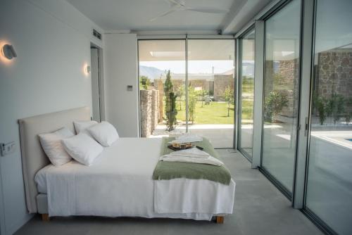 a bedroom with a white bed and glass doors at VARKO LUXURY SUITES in Paleros