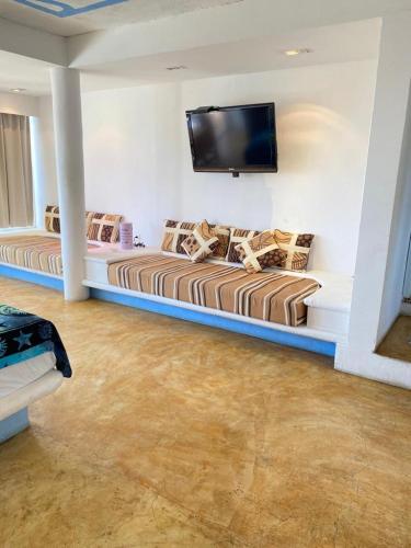 a living room with two beds and a flat screen tv at Casa de las Olas Surf & Beach Club in Acapulco