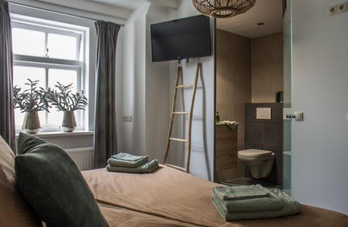a bedroom with a bed with a flat screen tv on the wall at Puur & Simpel, Buitengewoon vertoeven in de Brabantse Kempen in Westerhoven