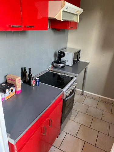 La cuisine est équipée de placards rouges et d'un four avec plaques de cuisson. dans l'établissement Appartement 2 pièces à Nevers, à Nevers