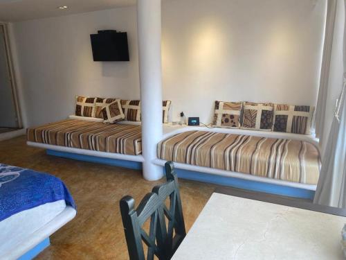 two beds in a room with a tv on the wall at Casa de las Olas Surf & Beach Club in Acapulco
