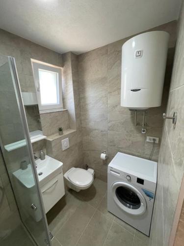 a bathroom with a toilet and a washing machine at Apartman Holiday in Tivat