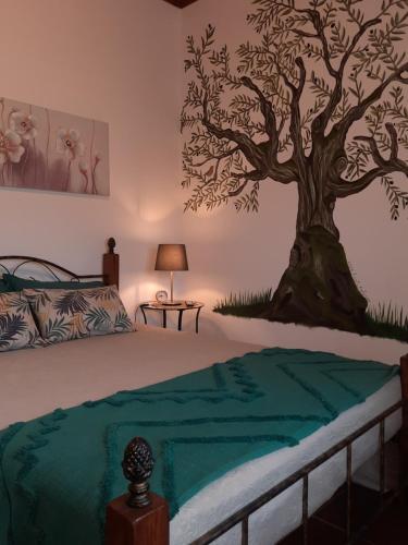 a bedroom with a tree mural on the wall at Casinha das Oliveiras in Bugios