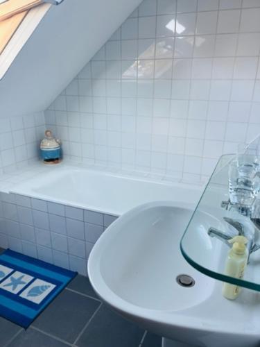 une salle de bain blanche avec un lavabo et une baignoire dans l'établissement Appartement Entre ville et nature, à Saint-Étienne-au-Mont