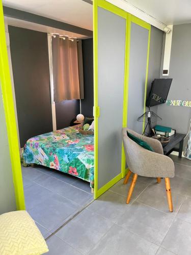 a bedroom with a bed and a chair and a desk at Les algues de La Chapelle Bleu horizon in Anse-Bertrand