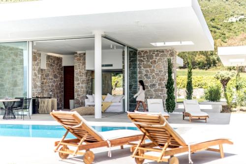 a villa with a swimming pool and a woman walking on a patio at VARKO LUXURY SUITES in Paleros