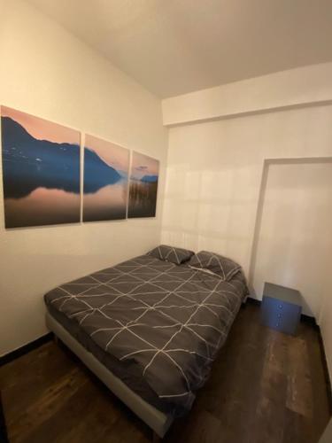 En cœur de ville في شامبيري: سرير في غرفة مع صورتين على الحائط