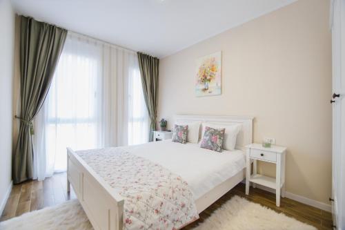 ein weißes Schlafzimmer mit einem weißen Bett und einem Fenster in der Unterkunft Olive Garden at West Residence in Oradea