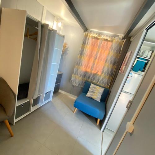 a small room with a blue chair and a curtain at Les algues de La Chapelle Bleu horizon in Anse-Bertrand