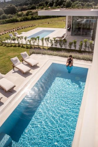 a woman is sitting in a swimming pool at VARKO LUXURY SUITES in Paleros