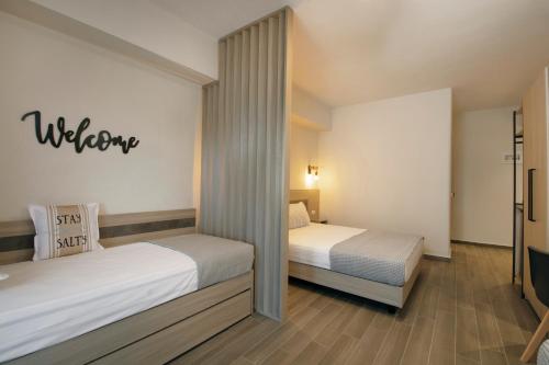 a bedroom with two beds and a welcome sign on the wall at Akti Liakada Hotel in Gerakini