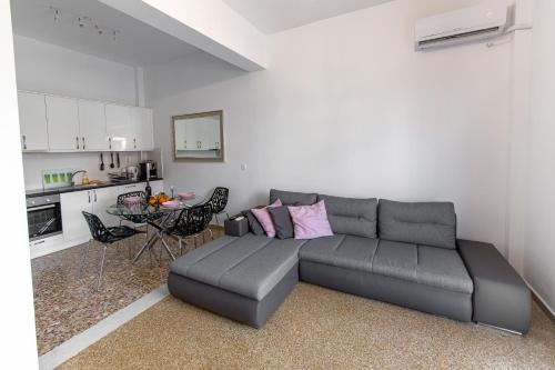 a living room with a gray couch and a kitchen at Fantastic location who love sea and center in Athens