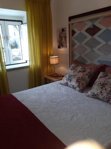 a bedroom with a large bed and a window at Casinha das Oliveiras in Bugios