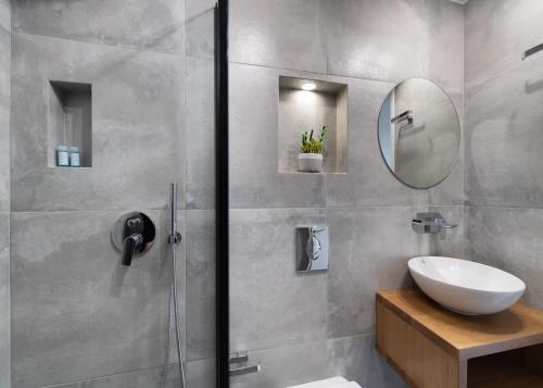 a bathroom with a shower with a sink and a mirror at chris apartement in Nydri