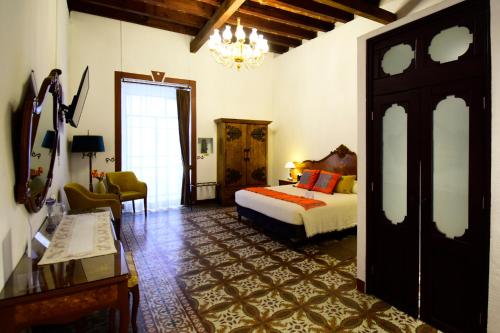 a bedroom with a bed and a chair and a table at Quinta Alhóndiga Galindo Hotel Boutique in Cholula